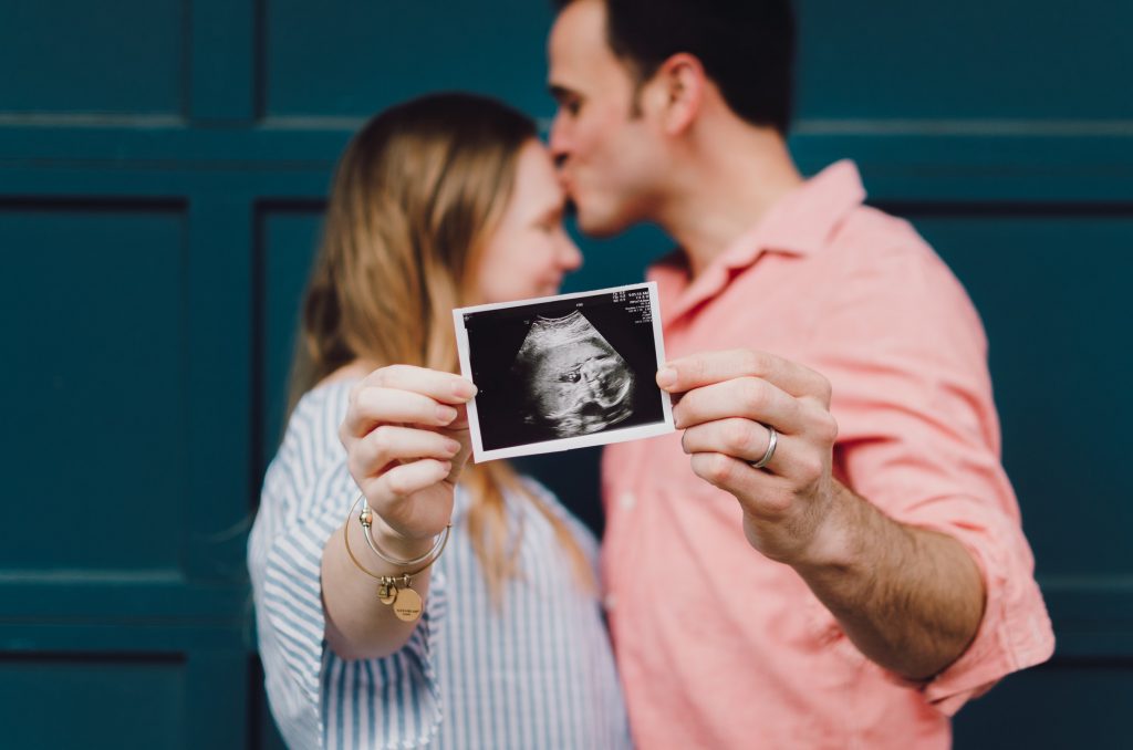 Maternity photoshoot couple holding baby ultrasound picture